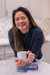 Dietitian Nutritionist and Owner of NCS in kitchen holding coffee mug